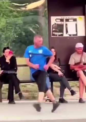 Кадр: Мужчина в синей футболке танцует на остановке под трек Bomfunk MC's