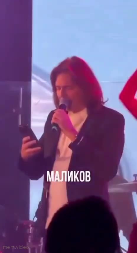 Кадр: Дмитрий Маликов поет и смотрит в телефон