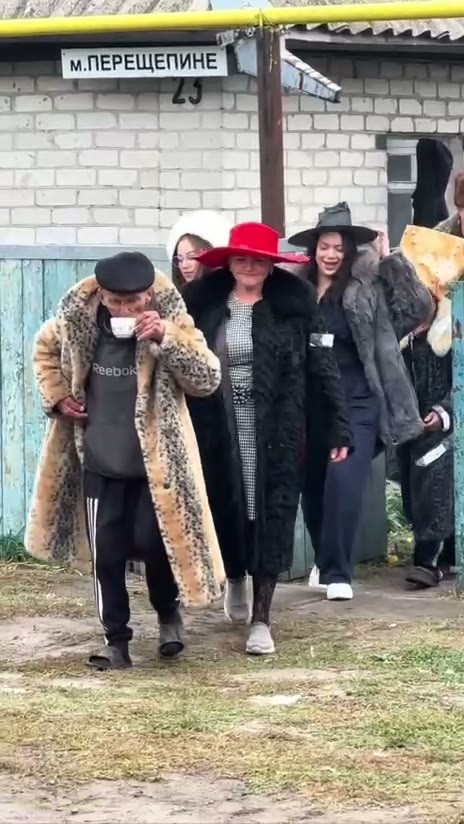 Кадр: Люди в шубах выходят из калитки синего забора