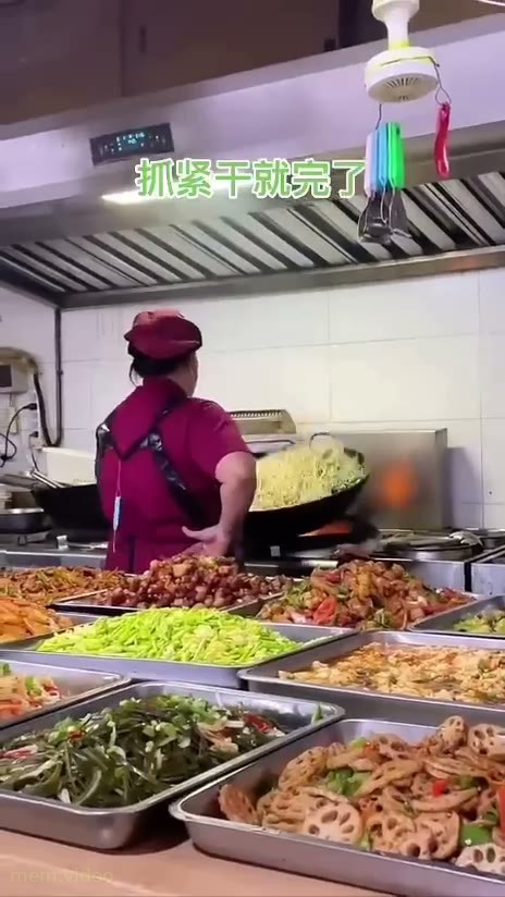 Кадр: Повар в красной форме жарит еду в огромном воке