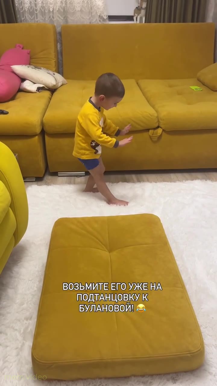Кадр: Маленький мальчик в жёлтой кофте задорно танцует дома
