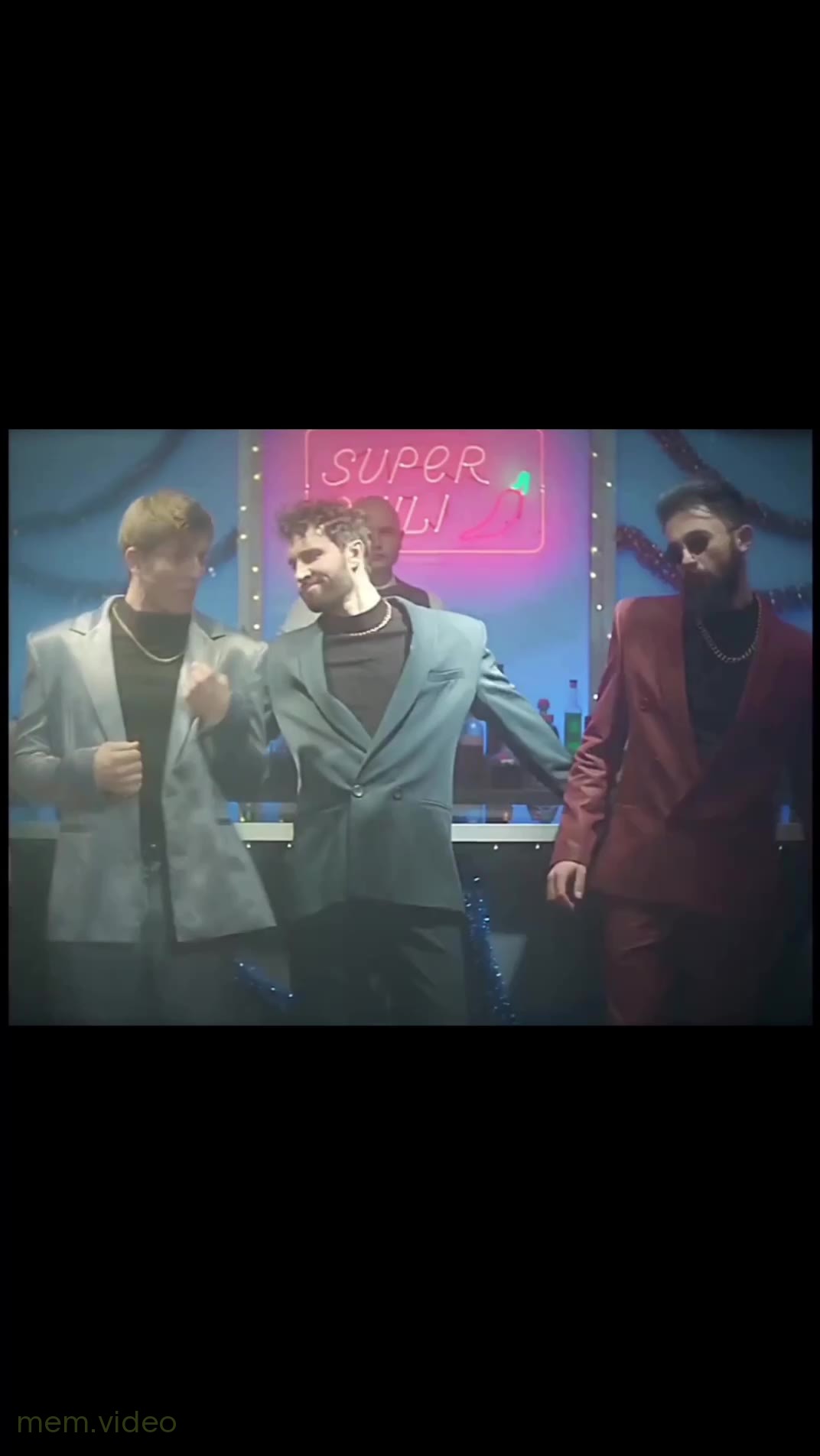 Кадр: "What is love?" — парни в костюмах танцуют у бара
